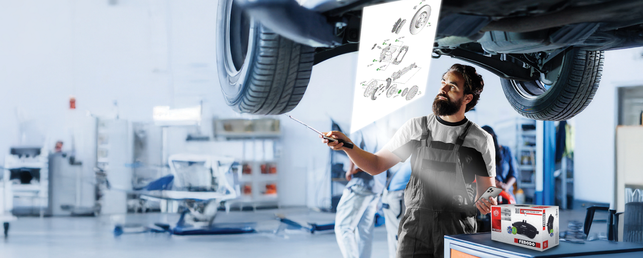 Installer in a garage using a smartphone under bright lighting after scanning a Ferodo QR code to access technical drawings for brake parts